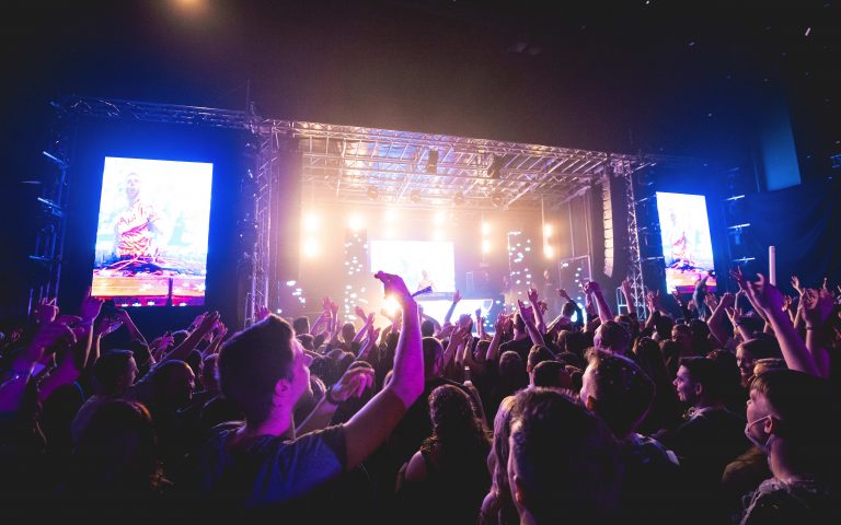 Festivalpublikum vor einer großen Bühne mit LED-Bildschirmen