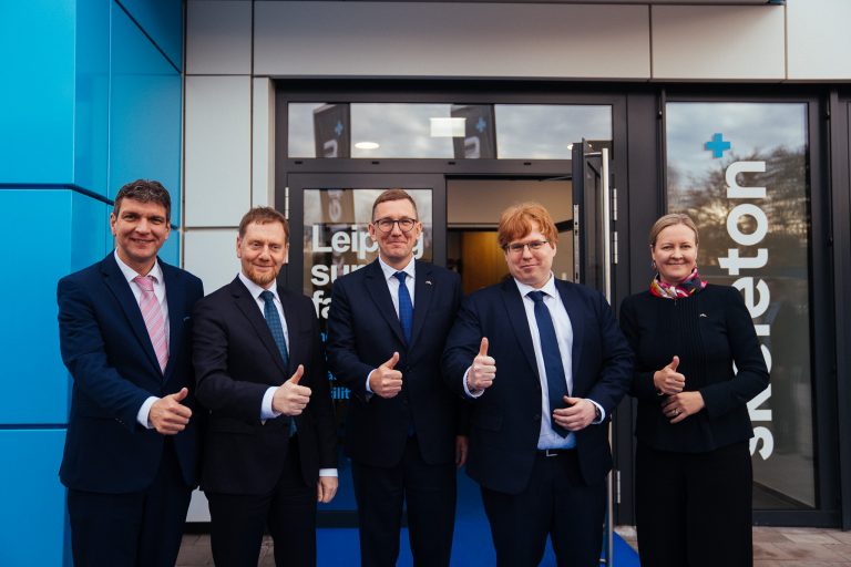 Gruppe vor dem Eingang der Skeleton Giga Factory bei der Werkseröffnung